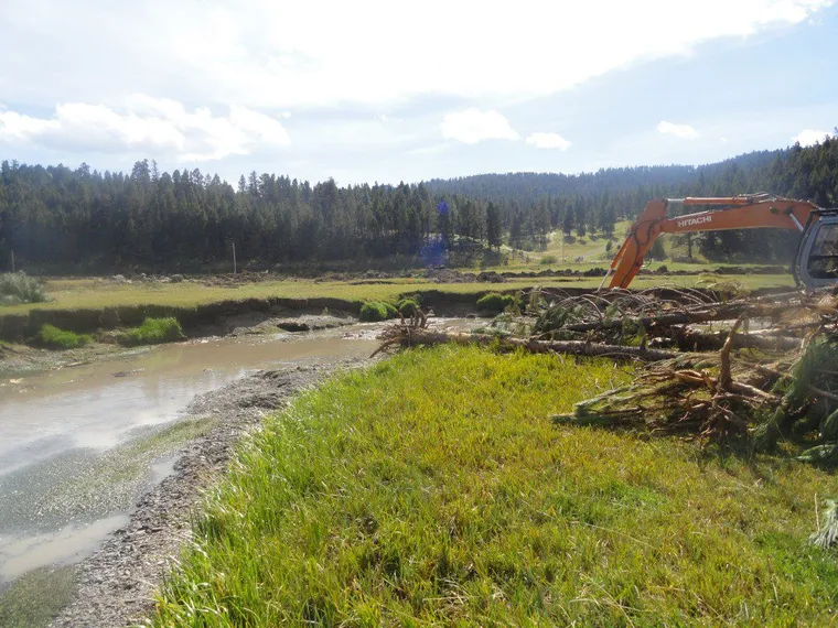 Excavator working a restored channel bend on a green floodplain Excavator working a restored channel bend on a green floodplain
